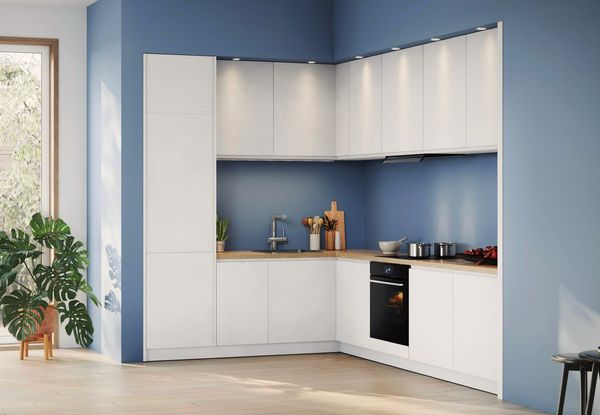 Bilden visar ett modernt vitt k&ouml;k, L-format. I k&ouml;ket syns vitvaror fr&aring;n Bosch.