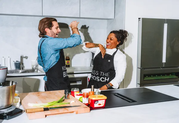 chefs in the kitchen giving a high five with bosch stainless steel refrigerator in the background