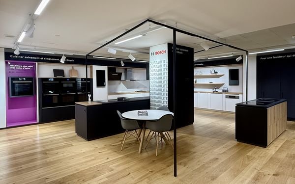Ampio showroom di cucine moderne con vari elettrodomestici, piani di lavoro e pavimenti in legno.