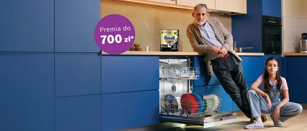 Dziewczyna i pan pozuja przy zmywarce w kuchni, na blacie kapsulki Finish