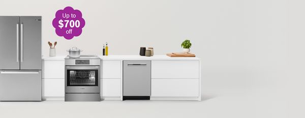 Modern kitchen with matching fridge, cooker and microwave surrounded by sleek cabinets in warm wood and an off-white tone