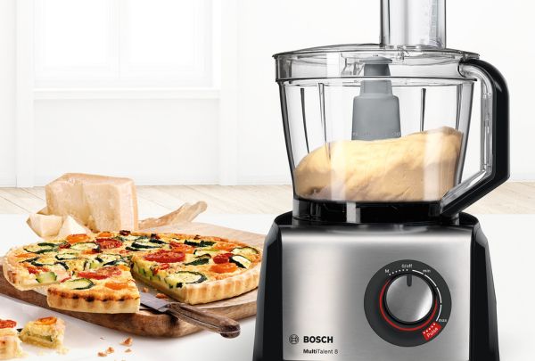 מעבד מזון של בוש וברקע מגש ועליו פשטידת ירקות