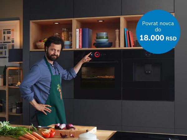 Čovek stoji u kuhinji ispred rerne.