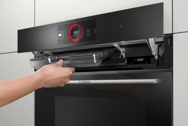 יד של אדם אוחזת במגירה שבתנור שחור של בוש