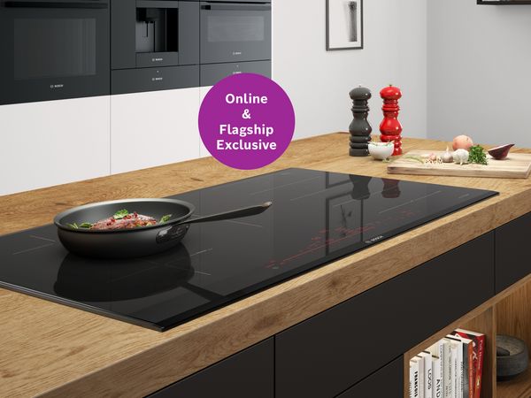 Modern kitchen featuring the Bosch accent|line PXV890DV5E induction hob with an icon highlighting its online and flagship experience centre exclusivity. 