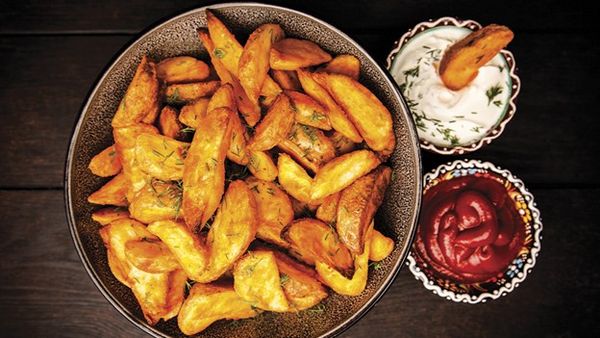 Golden potato wedges with ketchup and creamy dill dip.