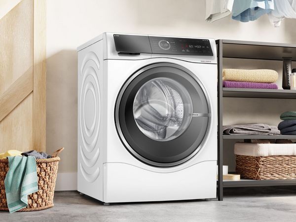 Een moderne wasruimte met een witte wasmachine en droger, met vers opgehangen kleren en een rieten mand gevuld 