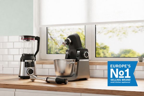 Elettrodomestici da cucina Bosch tra cui un frullatore, un miscelatore stand e un frullatore a mano su un piano di lavoro vicino a una finestra con l'etichetta "Marchio di vendita numero 1 in Europa".