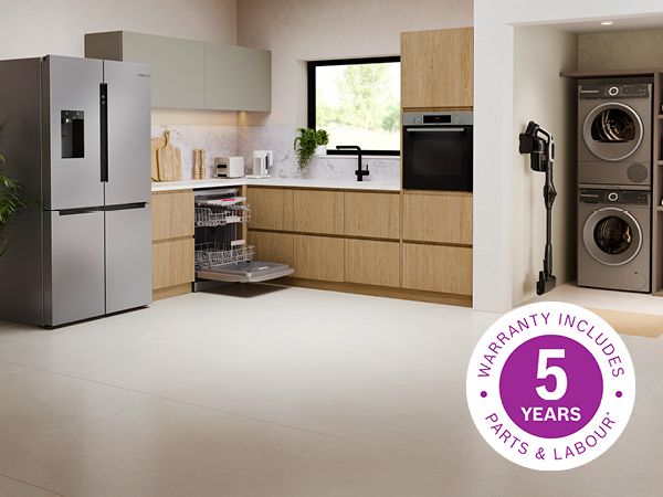 Modern kitchen featuring sleek black ovens built into white cabinetry, with a light-filled living area in the background.