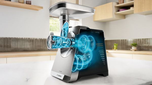 Tritacarne elettrico Bosch sul tavolo della cucina con sovrapposizione digitale che mostra ingranaggi interni e coclee.