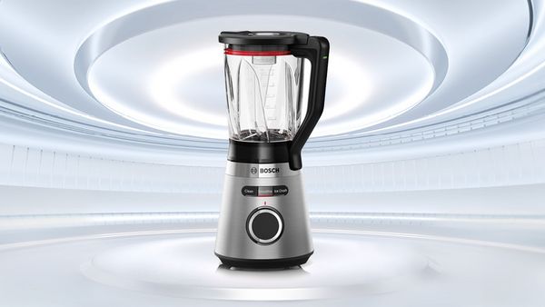 K&uuml;chenmixer von Bosch mit transparentem Beh&auml;lter und silbernem Geh&auml;use vor hellem, futuristischem Hintergrund mit blauem Kreis und wei&szlig;er Aufschrift 'Top Angebote' 