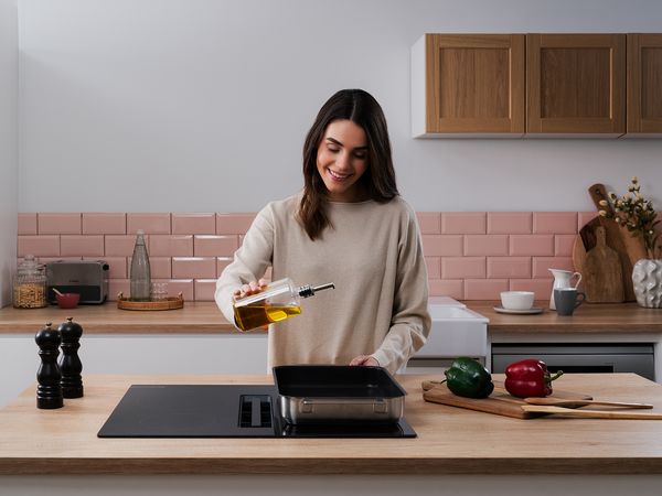Plan de cuisine avec grille de refroidissement, panier noir, casserole argent&eacute;e avec couvercle et trois tasses blanches.