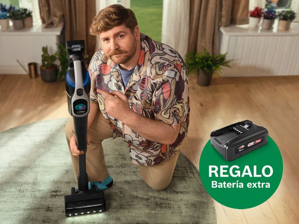 Persona arrodillada limpiando alfombra con aspiradora inal&aacute;mbrica Bosch; etiqueta verde: "REGALO Bater&iacute;a extra". 