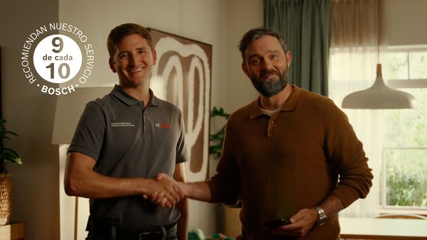T&eacute;cnico de servicio Bosch estrecha la mano de un cliente en una cocina, sello "9 de cada 10 recomiendan nuestro servicio".