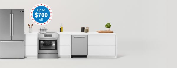 Modern kitchen with matching fridge, cooker and microwave surrounded by sleek cabinets in warm wood and an off-white tone