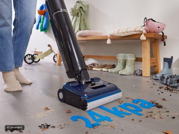 Eine Person reinigt mit dem Bosch Wischsauger den stark verschmutzten Eingangsbereich einer Familie mit kleinen Kindern.