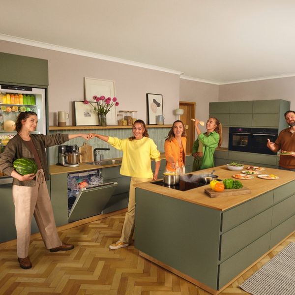 Moeder, vader en drie dochters in een keuken met groene accenten en verschillende Bosch huishoudapparaten.