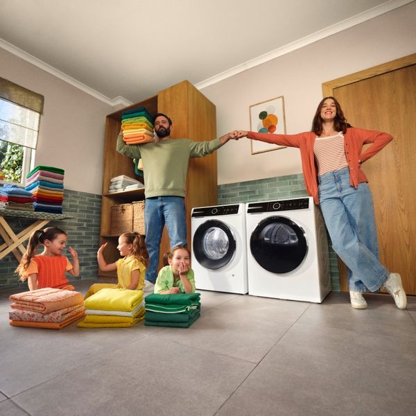 Gezin van 5 met stapels wasgoed met de Bosch wasmachine en droger in het middelpunt.
