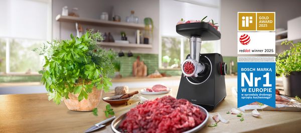 Białe urządzenie MultiPower Serie 4 z przystawką do mielenia mięsa obok burger&oacute;w i sałatki na blacie kuchennym.