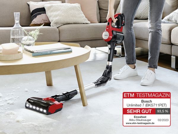 Frau saugt mit einem Bosch Unlimited Staubsauger Katzenhaare von Teppich ab. 
