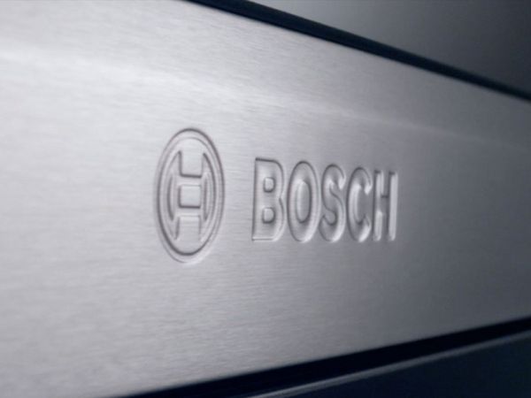 N&auml;rbild av Bosch-logotyp pr&auml;glad i borstat st&aring;l p&aring; fronten av en Bosch-produkt. 