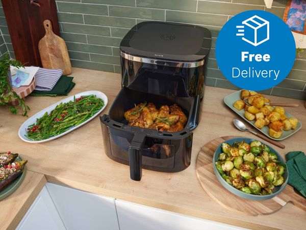 Bosch air fryer on kitchen countertop surrounded by food and with free delivery icon overlay