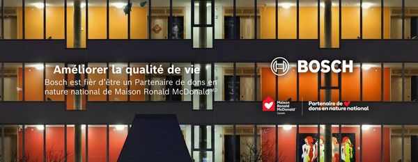 Fa&ccedil;ade d'un immeuble avec des fen&ecirc;tres &eacute;clair&eacute;es orange-jaune et un texte mentionnant que Bosch soutient Ronald McDonald House Charities Canada.