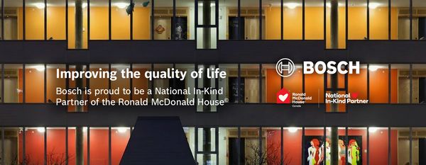 Building facade with orange-yellow lit windows and text about Bosch supporting Ronald McDonald House Charities Canada.
