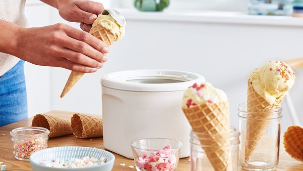Eine Person befindet sich in einer K&uuml;che und bef&uuml;llt Eiswaffeln mit selbstgemachtem Eis.