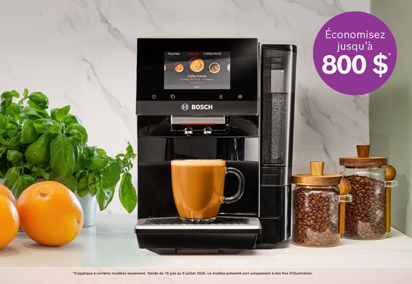 Machine &agrave; caf&eacute; Bosch qui pr&eacute;pare un latte avec des oranges, une plante de basilic et des bocaux de grains de caf&eacute; sur le comptoir de la cuisine.
