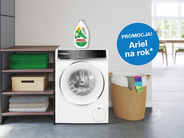 Jasna łazienka, pralka a na niej butelka płynu Ariel. pikrogram Promocja