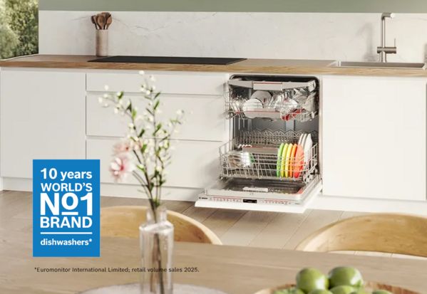 Bosch inbouwvaatwasser met open deur gevuld met kleurrijke borden in witte moderne keuken, met badge '10 years World's No1 Brand dishwashers'           