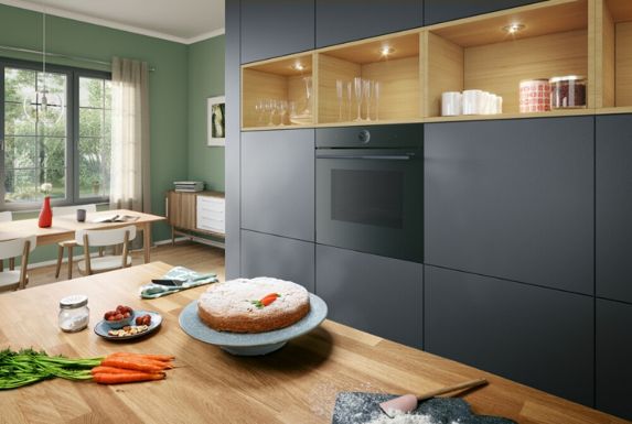 Dolce appena sfornato appoggiato sul piano di lavoro, con forno da incasso integrato in una cucina moderna sullo sfondo