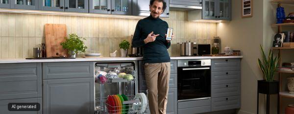 Uomo in una cucina moderna accanto a una lavastoviglie aperta, mentre mostra uno smartphone con un'app di controllo