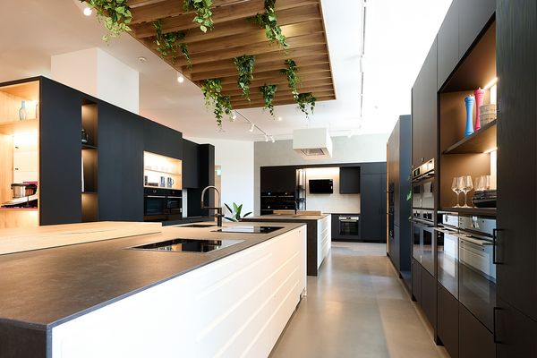 Moderne K&uuml;che mit Holzschr&auml;nken, wei&szlig;en Arbeitsplatten und Einbauger&auml;ten.
