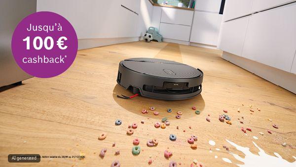 Aspirateur robot sur un sol de cuisine en bois parmi des c&eacute;r&eacute;ales color&eacute;es renvers&eacute;es et du lait ; en arri&egrave;re-plan un ballon et un jouet. En haut &agrave; gauche, un cercle violet portant la mention "Jusqu'&agrave; 100&euro; cashback*".