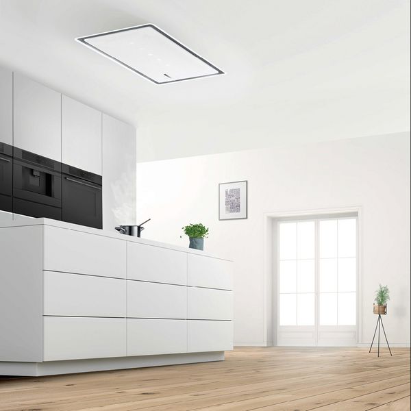 Moderne, minimalistische keuken met witte muren, houten planken, en een grote bovenlichtarmatuur.