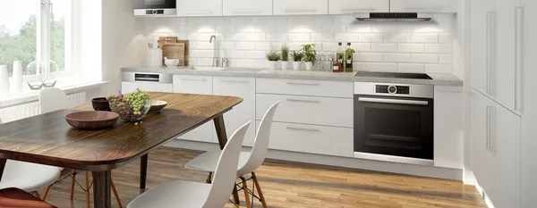  A bright room with a modern and white kitchen behind a dining table set with a wooden table and white chairs.