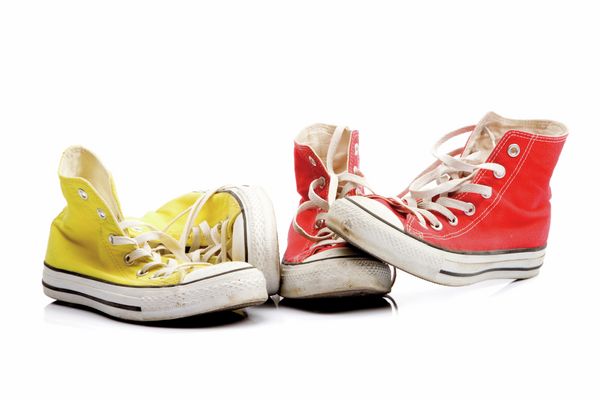 Due paia di sneakers, una gialla e una rossa, su fondo bianco