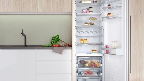 Küche mit einem geöffneten Kühlschrank, in dem Lebensmittel sind. 