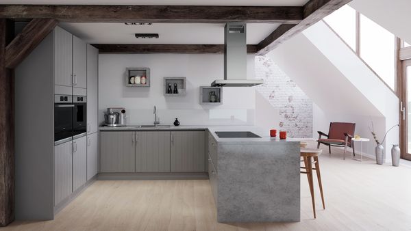 U-shaped farmhouse kitchen with grey vertical paneling and handles. Built-in Bosch oven and fully automated espresso maker in cabinets at left. Loft-style setting with exposed brick and mid-century furniture.  