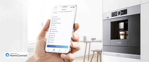 Smartfon z aplikacją Home Connect i rodzajami kawy do wyboru; w tle ekspres do kawy marki Bosch. 