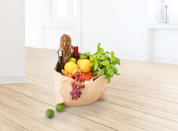 Polna papirnata vrečka, v kateri so raznorazna živila, na primer sveže sadje in zelenjava, kruh in vino.