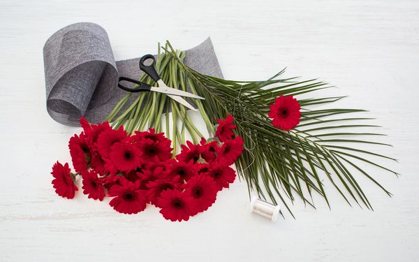 Exemple d'ornement d'une table parfaite : Un bouquet de fleurs rouges et de verdure mis en forme aux ciseaux.