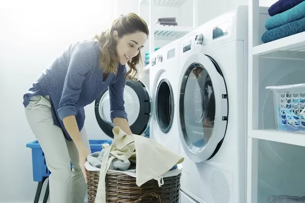 Femme en train de mettre des vêtements dans la laveuse