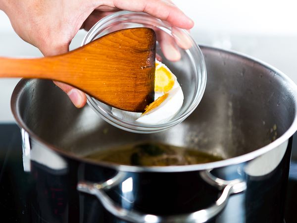 In the same pot, add in the egg and yolks while breaking them loose with a wooden spoon