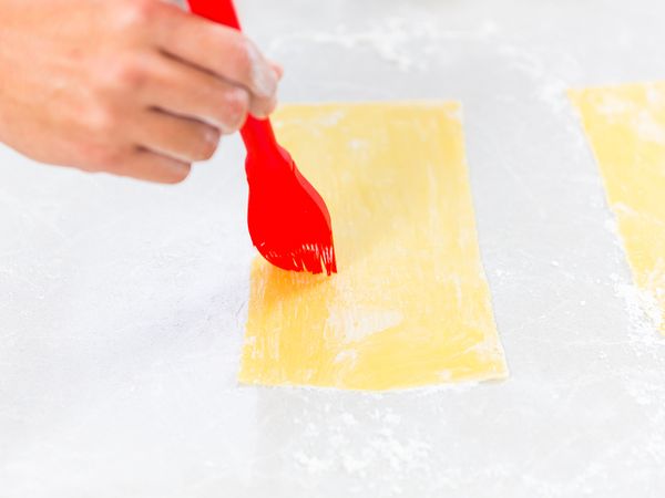 Brush the pasta sheets with water