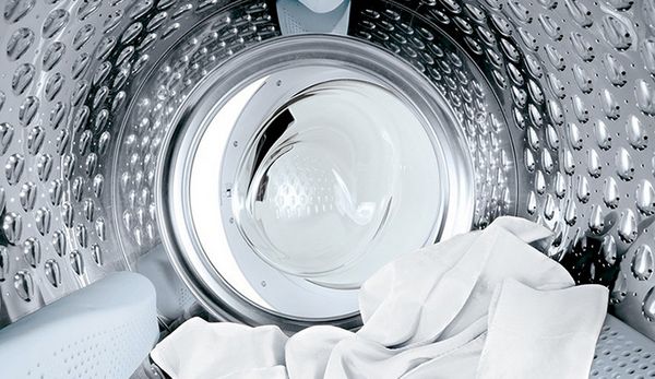 Interno del cestello di una lavatrice con panni bianchi all’interno.