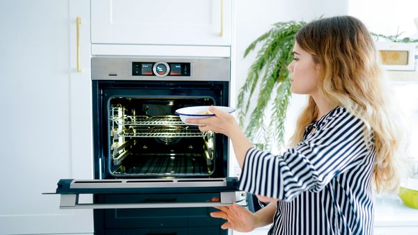 Women putting food dish in oven