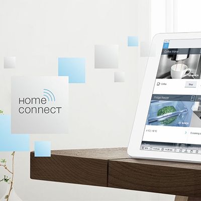 Salon meublé moderne, au premier plan un smartphone avec contrôle de la maison intelligente pour symboliser les fonctions à distance de Home Connect. 